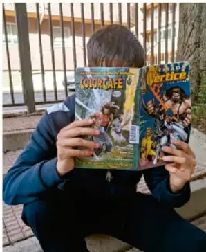 Adolescente sentado leyendo una revista cómica, ilustrando la vida cotidiana del estudiante