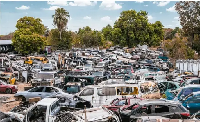 Fotografía de un depósito de chatarra con cientos de automóviles desechados, que ilustra la acumulación de residuos y la contaminación.