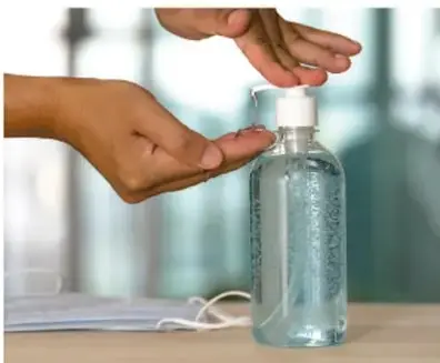 Manos aplicando líquido antibacterial de un botella sobre otra mano.