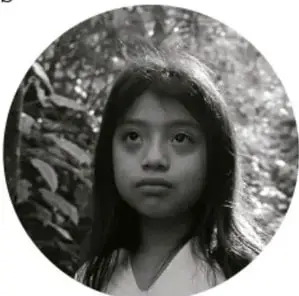 Fotografía en blanco y negro de una niña indígena mirando a la cámara.