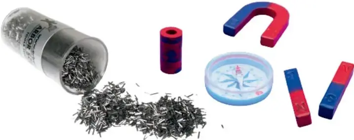 Fotografía de materiales de experimentación magnética: frasco de plástico con limaduras de hierro derramadas, imán cilíndrico pequeño, imán en herradura azul y rojo, brújula de plástico y dos imanes de barra con extremos rojo (N) y azul (S).
