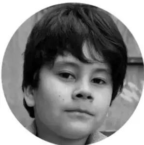 Fotografía en blanco y negro, en óvalo, del rostro de un niño de cabello oscuro que mira a la cámara.