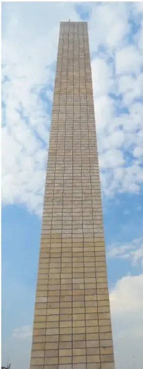 Fotografia del monumento Estela de Luz, torre vertical de color claro con estructura de cuadricula, bajo un cielo con nubes.