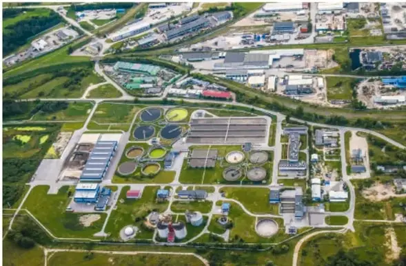 Vista aérea de una planta de tratamiento de aguas residuales con piscinas de aireación y edificios industriales.