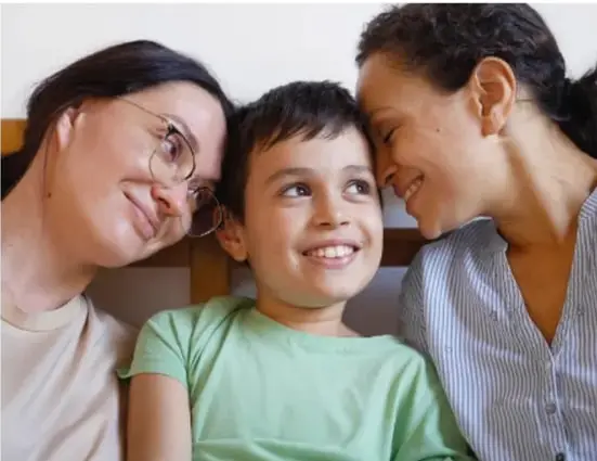 Fotografía de una familia (dos mujeres y un niño sonriendo juntos) que ilustra la convivencia familiar.