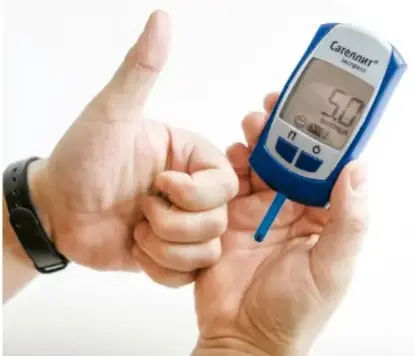 Manos midiendo el nivel de glucosa en sangre con un glucómetro (marca Contour), haciendo la señal de pulgar arriba.