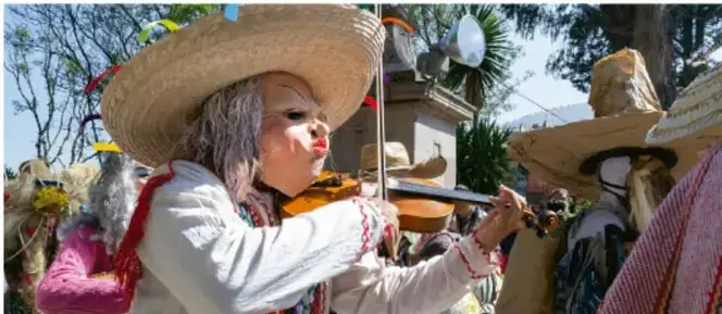 Fotografía de una celebración comunitaria en Baja California: personas con sombreros de paja y vestimenta tradicional; una mujer toca el violín. Crédito: Sandra Angélica Martínez Cruz.