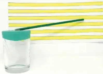 Fotografía de un barómetro casero: vaso transparente con globo verde en la boca, popote inclinado y fondo con líneas amarillas y blancas que sirven de escala.
