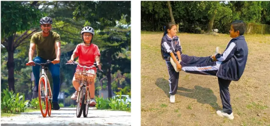 Un adulto y una niña montan bicicletas en un camino arbolado, ambos con casco.