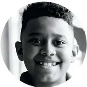 Fotografía de un niño sonriente con fondo claro, que ilustra la participación de los estudiantes.