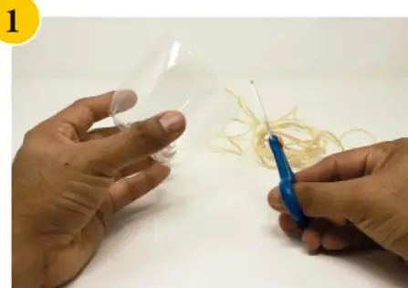 Manos cortando con tijeras la botella de plástico para formar el recipiente.