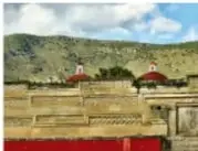 Fachada del Palacio de Mitla con estructura de piedra y vegetación circundante.