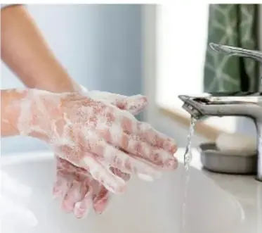Persona lavándose las manos con abundante espuma bajo un grifo, ilustrando medidas de higiene de la vía digestiva.