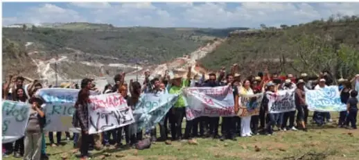 Grupo de personas con pancartas en una zona rural, aparentemente en una protesta o marcha.