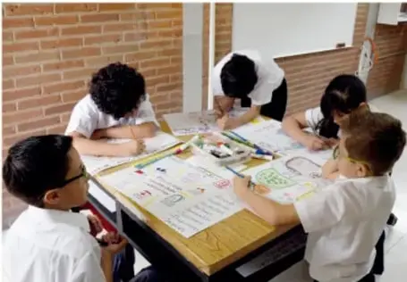 Niños y niñas elaborando una maqueta sobre una mesa en el aula.