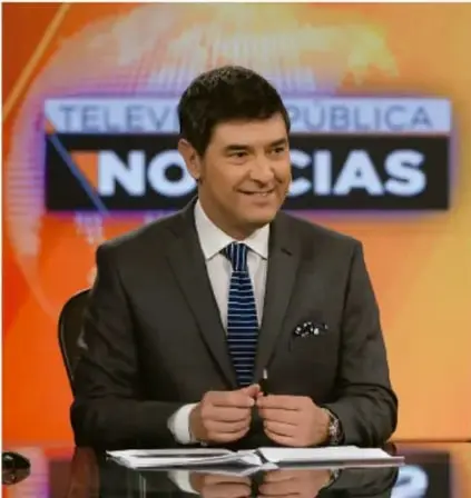 Fotografía de un presentador de noticias en el set de un programa titulado "Televisión Pública Noticias", ilustrando los medios de comunicación masivos.