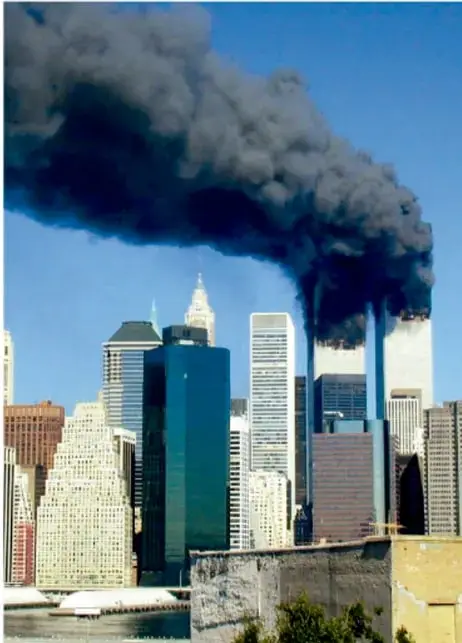 Fotografía de la ciudad de Nueva York con una enorme columna de humo negro que emana de las Torres Gemelas del World Trade Center tras el ataque, con los rascacielos del centro de Manhattan al fondo bajo cielo azul.