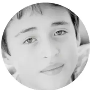 Fotografía en blanco y negro del rostro de un niño mirando de frente, dentro de un círculo.