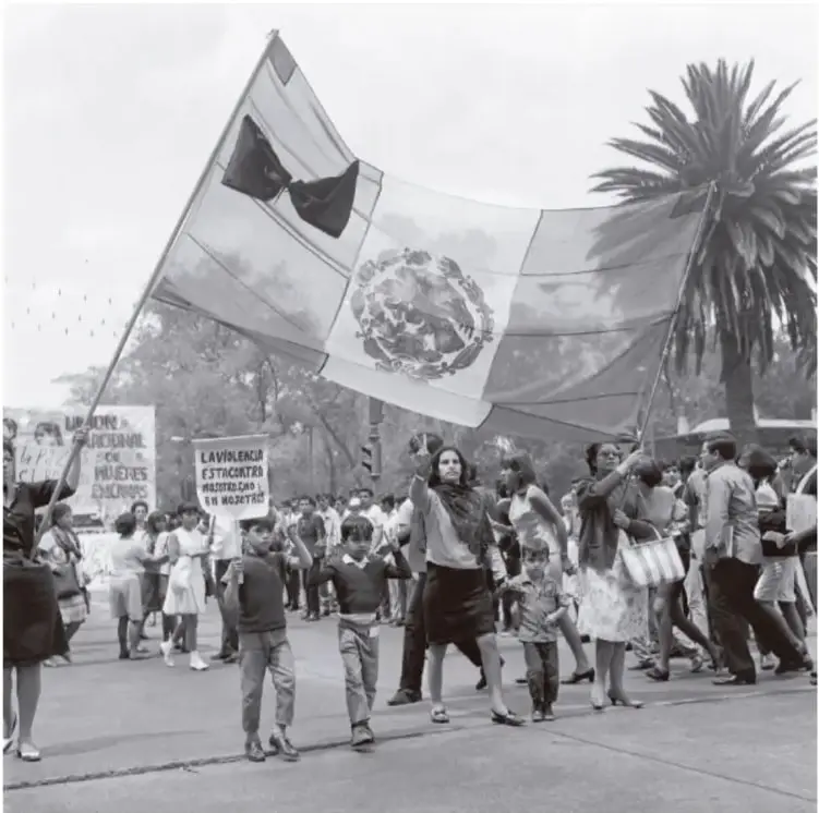 Fotografía en blanco y negro: mitin de octubre de 1968 con mujeres y niños portando una bandera de México de gran tamaño y pancartas de protesta; al fondo, una palmera y la multitud. Pie de foto: «Mitin de señoras por la liberación de sus hijos detenidos, octubre de 1968, Archivo Histórico de la UNAM».
