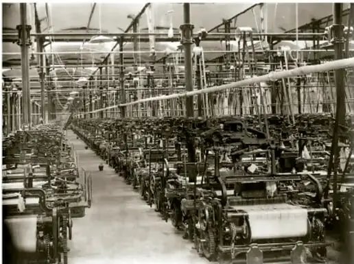 Foto histórica del interior de una fábrica textil con hileras de máquinas hiladoras; ilustra la producción industrial.