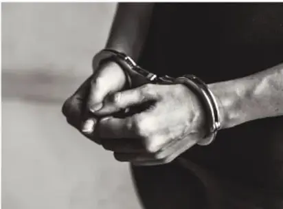 Manos esposadas en blanco y negro, símbolo de privación de la libertad.