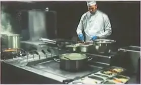 Cocinero preparando alimentos en una cocina.