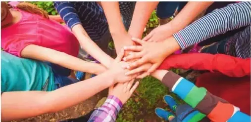 Niños y niñas de diferentes grupos colocan sus manos juntas. La imagen representa la inclusión y el acceso a la educación como elementos de la unidad nacional.