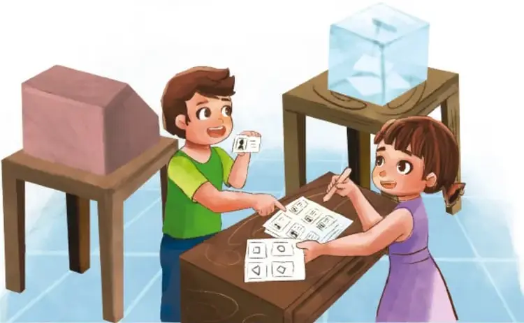 Ilustración de dos estudiantes frente a un escritorio preparando una obra teatral: uno sostiene una tarjeta con un personaje y una urna transparente, la otra escribe en un guion con personajes dibujados; hay un escenario con recinto de cartón y una mesa con urna.