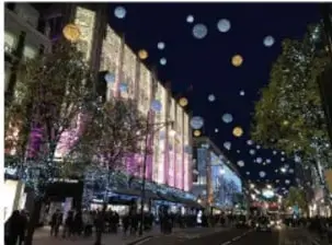 Calle comercial nocturna iluminada con luces y decoración navideña.