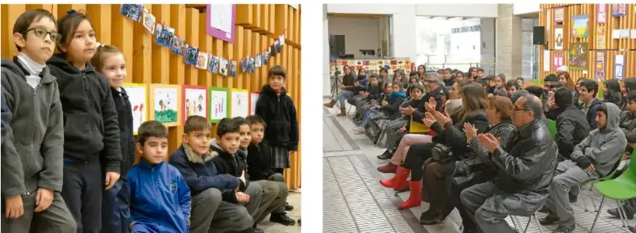 Grupo de estudiantes de primaria de pie y sentados frente a un muro con dibujos y trabajos escolares.