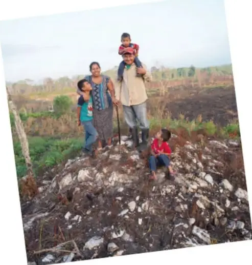 Familia campesina de pie en un terreno, con niños y adultos, representando la vida comunitaria.