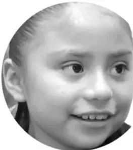Fotografía en blanco y negro del rostro sonriente de una niña, mirando hacia un lado.