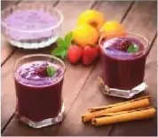 Vasos de colada morada junto a frutas y guaguas de pan, relacionados con el Día de los Difuntos.