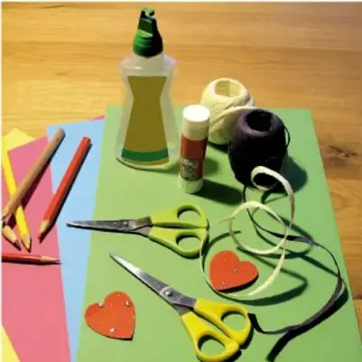 Fotografía de materiales escolares: cartulinas de colores, tijeras, pegamento, colores y regla sobre una mesa.