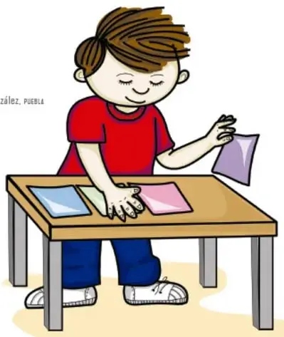 Niño sonriente de camiseta roja y pantalón azul sosteniendo en cada mano hojas de papel de colores (morada, rosa y verdes).