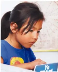 Fotografía de una niña con playera azul escribiendo o dibujando en un cuaderno, como ejemplo de estudiante investigando.