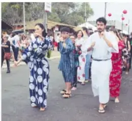 Fotografía de personas con trajes tradicionales en una calle, en una celebración o desfile comunitario.