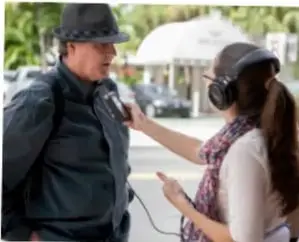 Una persona entrevistando a un policía con micrófono y audífonos.