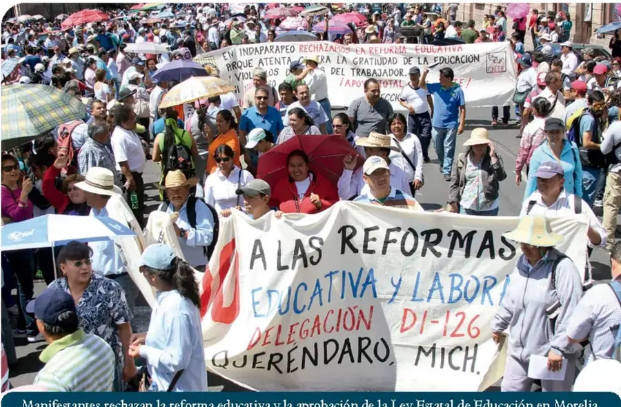Fotografía de una marcha multitudinaria con mantas que dicen 'A las reformas educativa y laboral' y 'En Indaparapeo rechazamos la reforma educativa'. Al pie: 'Manifestantes rechazan la reforma educativa y la aprobación de la Ley Estatal de Educación en Morelia'.