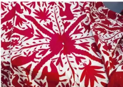 Mujeres indígenas sentadas en un salón vistiendo trajes tradicionales rojos con cintas de colores (posibles trajes triquis).