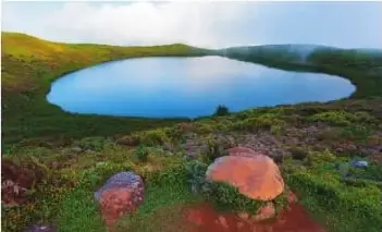 Fotografía de la laguna El Junco, rodeada de vegetación y terrenos elevados.