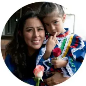 Fotografía circular de una mujer abrazando a una niña con vestido tradicional.