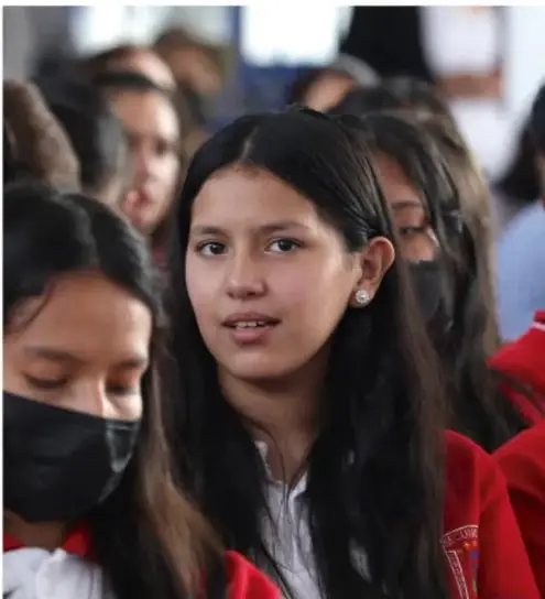 Grupo de estudiantes de secundaria reunidos, uno de ellos hablando, representando la asamblea de reflexión.