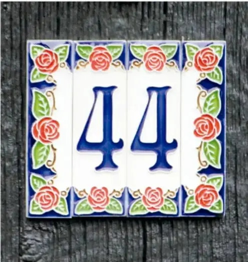 Placa de número de casa con los azulejos decorados con rosas y el número 44 en azul.