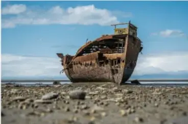 Fotografía de un barco oxidado varado en la playa, ilustrando la corrosión como proceso exotérmico.