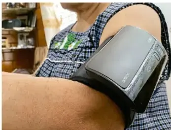 Fotografía de una persona con un brazalete de esfigmomanómetro (tensiómetro) colocado en el brazo, usado para medir la presión arterial.