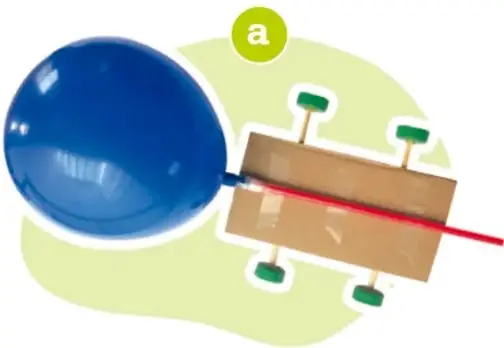 Globo azul conectado mediante un popote a un carrito de madera con cuatro llantas verdes.