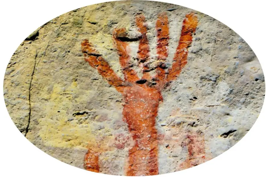 Foto ovalada de una pintura rupestre roja en forma de mano abierta sobre una roca de tonos ocres y grises, típica del arte rupestre de Aguascalientes.