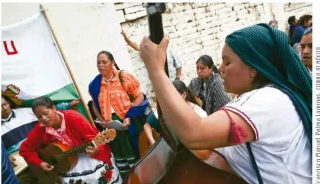 Fotografía de un grupo de mujeres indígenas en una actividad cultural comunitaria, algunas tocando instrumentos musicales (guitarra, contrabajo) y una con un estandarte; crédito: Francisco Manuel Parina Jayo, Ludmila de Jesús López.