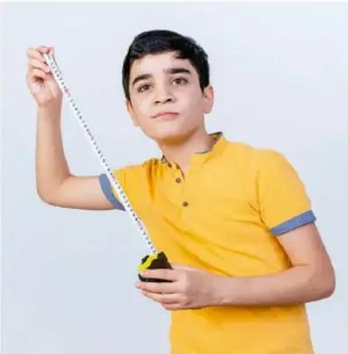 Estudiante con playera amarilla sosteniendo una cinta métrica extendida, como ejemplo de medición convencional de longitud.